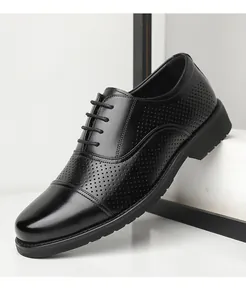 Macro view of black leather dress shoes featuring elegant perforated patterns for breathability.