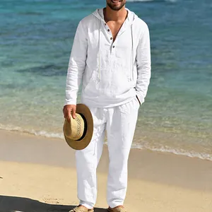 Mann in weißem Leinen-Langarm-Henley-Hemd mit Kapuze und passender Hose am Strand