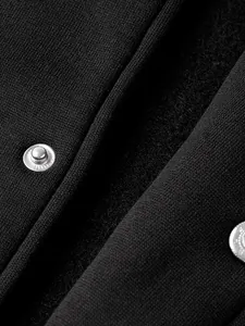 Close-up of black knit fabric texture and silver metal snap buttons on baseball jacket