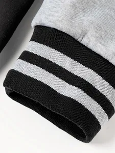 Close-up of ribbed black and white striped cuffs on a grey men's baseball jacket detail.