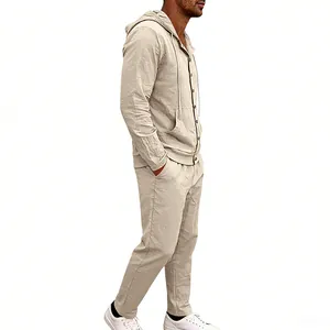 Side profile view of a man wearing a loose beige linen hooded shirt and matching trousers set