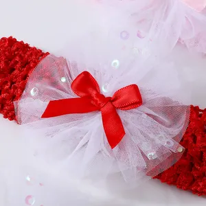 Close-up of red crochet baby headband with white tulle flower and red ribbon bow
