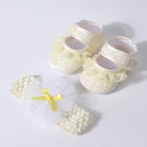 Detail view of cream lace baby walking shoes and matching tulle flower headband set.