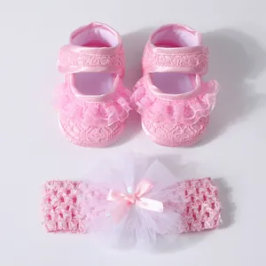 Detail shot of pink lace baby walking shoes with matching bow headband gift set.