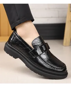 Vista detallada de mocasines de cuero negro con suela gruesa y detalle de hebilla.