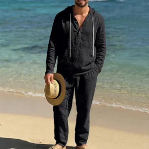 Lässiges schwarzes Herren-Leinen-Set mit Kapuze und Hose an einem tropischen Strand