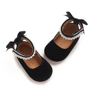 Detailed macro view of black baby girl princess shoes featuring cute bow and pearl strap details