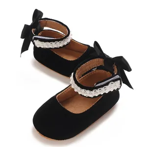 Close-up of black baby princess shoes with pearl straps and satin bows