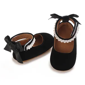 Close-up detail view of black velvet baby girl princess shoes with pearls and silk bow