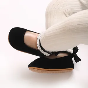 Detail of black velvet baby girl princess shoes with pearl lace trim and ribbon bow decoration