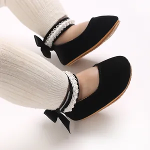 Close-up of black velvet baby princess shoes with bow and pearl strap details.