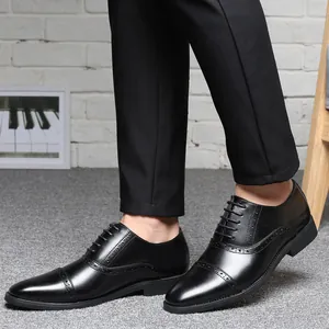 Detalle de zapatos Oxford de cuero negro para hombre con perforaciones brogue decorativas.