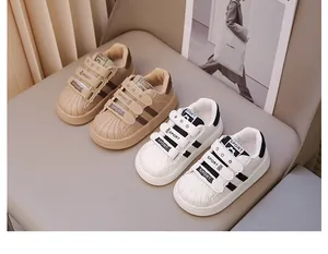 Λεπτομερής προβολή των παιδικών sneakers shell-toe σε κομψό μπεζ και λευκό χρώμα.