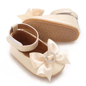 Nahaufnahme eleganter beige Baby-Prinzessin-Schuhe mit Strass-Schleife und weicher Sohle.
