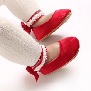 Close-up of red velvet baby girl princess shoes with bow and pearl ankle strap details