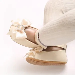 Nahaufnahme cremefarbener Baby-Prinzessinenschuhe für Kleinkinder mit Strass-Perlen-Schleife.