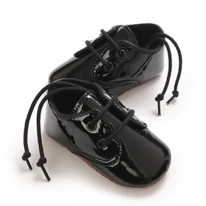 Primo piano di scarpe per neonati in vernice nera lucida con lacci di sicurezza