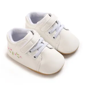Primer plano de zapatillas blancas para bebé con cordones azules y bordados