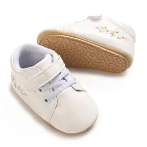 Vista detallada de zapatillas blancas para bebé con bordado floral y suelas de goma antideslizantes