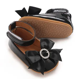 Nahaufnahme der schwarzen Lack-Prinzessin-Babyschuhe mit Strassschleife und Weichsohle