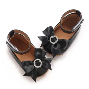 Detailansicht schwarzer Lackleder-Babyschuhe mit dekorativen Strassschleifen