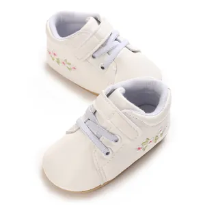 Detalle de zapato deportivo blanco para bebé con bordado de flores y velcro