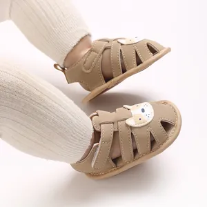 Vista detallada de sandalias beige para bebé con diseño de perro sobre calcetines blancos