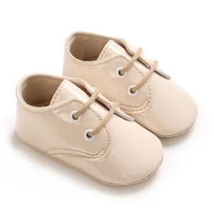 Dettaglio macro di scarpine per neonati in vernice beige con suole morbide antiscivolo.
