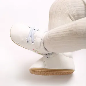 Detalle de zapatillas blancas para bebé con bordado floral y suelas blandas antideslizantes