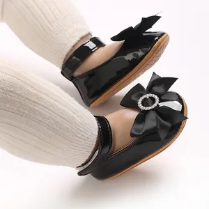 Nahaufnahme schwarze Lackleder-Prinzessinenschuhe für Babys mit einer Strass-Schleife