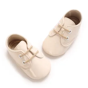 Dettaglio scarpe neonato in pelle verniciata beige lucida con lacci