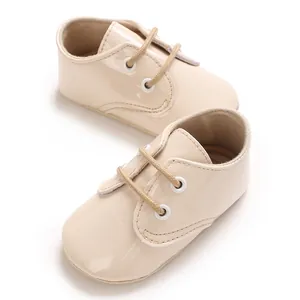Vista dettagliata delle scarpe per neonati in pelle verniciata beige con lacci frontali