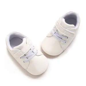 Primer plano de zapatillas blancas para bebé con cierre de velcro y cordones elásticos decorativos
