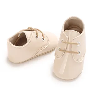 Vista dettagliata di scarpe primi passi per neonati in pelle verniciata crema con lacci.
