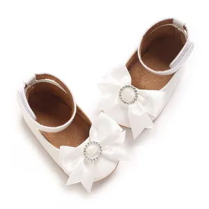 Detail weißer Baby-Prinzessin-Schuhe mit großer Satinschleife und Strass-Verzierung