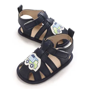 Detalle de sandalias azul marino para bebé niño con parche de camión de dibujos animados.