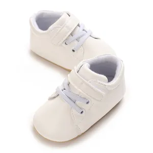 Primer plano detallado de zapatillas blancas para bebé con tira de velcro y cordones grises