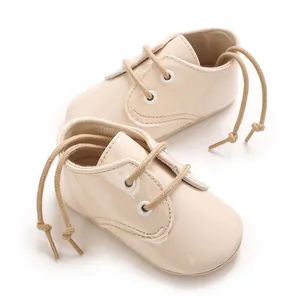 Primo piano di scarpe primi passi beige lucide per neonati con lacci morbidi