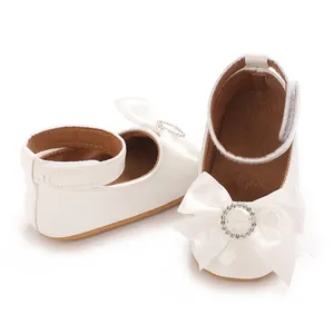 Nahaufnahme weißer Baby-Prinzessinenschuhe mit Strass-Schleife und Knöchelriemen