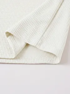 Detailed macro view of white waffle knit fabric texture and neat double stitching hem