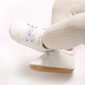 Primer plano de zapatillas blancas para bebés con suelas de goma marrones antideslizantes