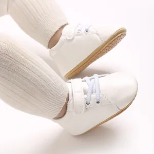 Primer plano de zapatillas blancas para bebé con leggings de punto en color crema