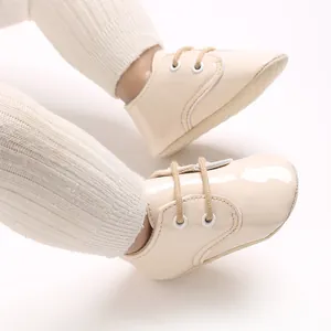 Primo piano di scarpe da bambino in pelle verniciata color crema con suola morbida