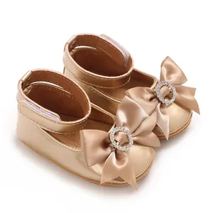 Nahaufnahme von goldenen Baby-Prinzessinenschuhen mit funkelnder Strassschleife und Weichsohle