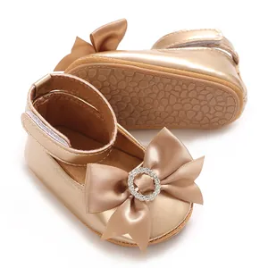 Nahaufnahme goldener Baby-Prinzessin-Schuhe mit Strass-Schleife und weicher, rutschfester Sohle.