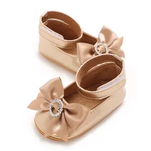 Detailansicht goldener Baby-Prinzessinenschuhe mit einer großen Satin-Strassschleife