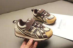 Detalle de la textura de malla y velcro de las zapatillas retro marrones para niños.
