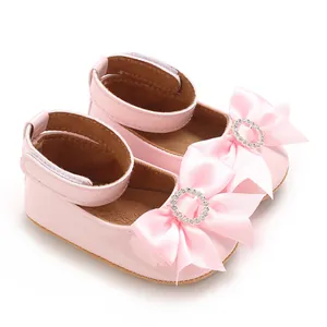 Vue détaillée de chaussures bébé princesse roses avec nœud en satin et détails de strass.