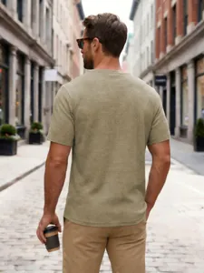Back view of a men's beige waffle knit short sleeve t-shirt in a street setting.