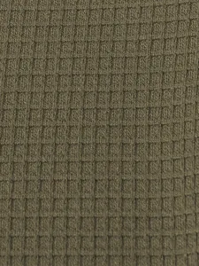 Close-up of olive green waffle knit fabric texture on a men's summer Henley t-shirt